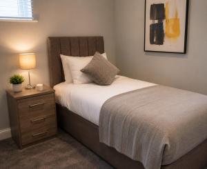 a bedroom with a bed with a nightstand and a bed sidx sidx sidx sidx at K Suites - Walsingham Close in Hatfield