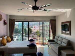 a bedroom with a bed and a couch and a ceiling fan at Smile Home in Patong Beach