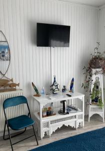 a white table with a chair and a television on a wall at Au Pré Fleury in Fleury-en-Bière