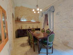 a dining room with a wooden table and green chairs at Il- Pellikan Farmhouse in Għajnsielem