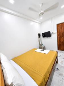 a white room with a bed with a yellow blanket at LS Residency Ac in Thiruchendur