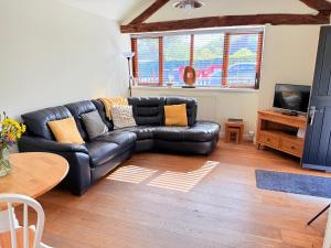 a black leather couch in a living room with a table at Smithy Cottage in Berriew
