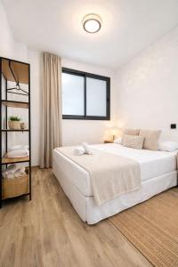 a white bedroom with a large bed and a window at LEMIGA SUiTE VALENCIA in Valencia