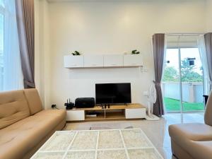 a living room with a couch and a flat screen tv at พิภูตะวัน วิลล่า in Ban Luam