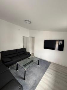 a living room with a black couch and a glass coffee table at Deluxe Apartment II in Velpke