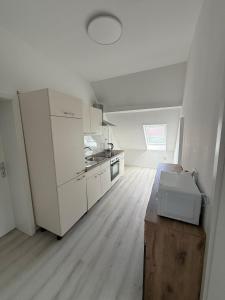 a kitchen with white cabinets and a wooden floor at Deluxe Apartment II in Velpke