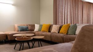 a living room with a brown couch with colorful pillows at Het Kasterhuis - Gastenverblijf in Wetteren +55 photos