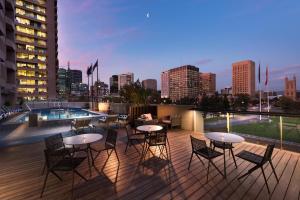 a rooftop deck with tables and chairs and a city skyline at Amora Hotel Adelaide in Adelaide