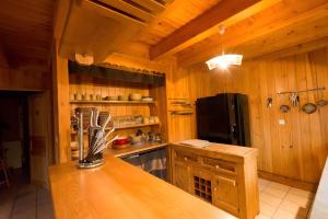 a kitchen with wooden walls and a black refrigerator at Chalet Bien-être, Piscine, Spa in La Chapelle-dʼAlagnon