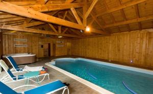a pool in a room with wooden walls and blue chairs at Chalet Bien-être, Piscine, Spa in La Chapelle-dʼAlagnon