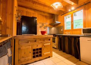 a kitchen with a tv on a wooden wall at Chalet Bien-être, Piscine, Spa in La Chapelle-dʼAlagnon +3 photos