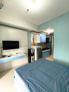 a bedroom with a bed and a flat screen tv at Studio Apartemen Parahyangan Residence by Anton in Bandung
