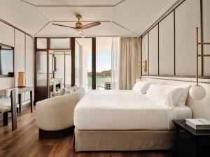 a bedroom with a large white bed and a living room at BLESS Ibiza The Site - New Opening 2026 in Playa d'en Bossa