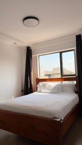 ein Schlafzimmer mit einem großen Bett und einem Fenster in der Unterkunft Bloomstays Furnished Apartments Nairobi - Two Bedroom With Sauna Gym & Workspace in Nairobi