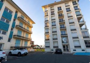 two tall buildings with cars parked in a parking lot at Appartement à la Centrale avec vue Océan in Soorts-Hossegor