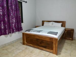 a bedroom with a wooden bed with purple curtains at Belle view Villa in Serekunda