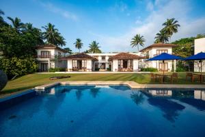 a villa with a swimming pool in front of a house at Kumu Beach By Teardrop Hotels in Balapitiya