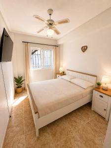 a bedroom with a bed and a ceiling fan at Almohabenos Pool View in Punta Prima +2 photos