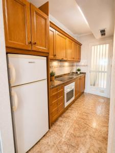 a kitchen with wooden cabinets and a white refrigerator at Almohabenos Pool View in Punta Prima