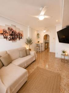 a living room with a couch and a flat screen tv at Almohabenos Pool View in Punta Prima