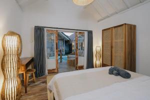a bedroom with a bed and a desk and a window at Tanahi Gili Air in Gili Islands