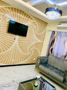 a room with a couch and a tv on a wall at Kër-Mame Tawfekh in Thiès