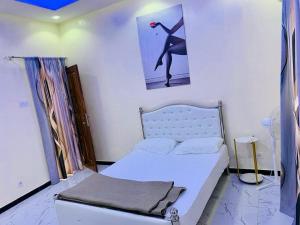 a small bedroom with a bed and a picture of a woman at Kër-Mame Tawfekh in Thiès