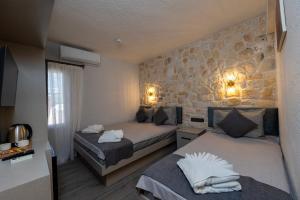 a bedroom with two beds and a stone wall at Nova Prime in Bodrum City