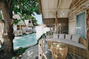 a patio with a couch next to a swimming pool at Tanahi Gili Air in Gili Islands