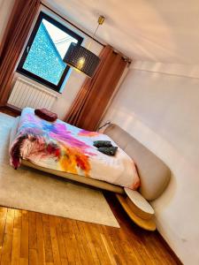 a bedroom with a bed with a colorful comforter and a window at Private room with king size bed - shared bathroom in Clavier