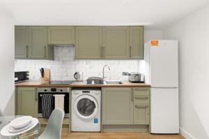 a kitchen with a washing machine and a refrigerator at Bright 2BR Flat Close to Shops in Beckenham in Beckenham