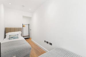 a white room with a bed and a mirror at Bright 2BR Flat Close to Shops in Beckenham in Beckenham