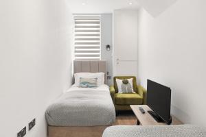 a bedroom with a bed and a tv and a chair at Bright 2BR Flat Close to Shops in Beckenham in Beckenham