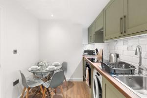 a kitchen with a sink and a table with chairs at Bright 2BR Flat Close to Shops in Beckenham in Beckenham +17 photos