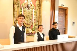 a group of three people standing behind a counter at Hotel Siya Grand in Tirupati