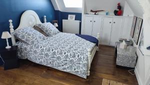 a bedroom with a bed and a blue wall at Ty Maen - Étage avec chambre, coin salon, toilettes et salle de bain in Erdeven