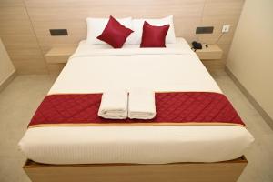 a bedroom with a large bed with red pillows at Hotel Siya Grand in Tirupati +10 photos