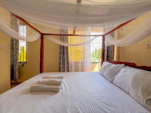 a bedroom with a large white bed with a window at Fiche Villas in Mombasa +62 photos