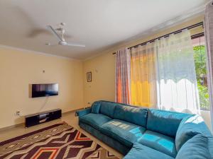 a living room with a blue couch in front of a window at Fiche Villas in Mombasa