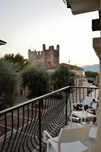 a balcony with white chairs and a castle in the background at Junior Suite agli Archetti in Torri del Benaco