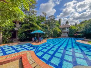 a swimming pool with a blue tile floor and an umbrella at Fiche Villas in Mombasa