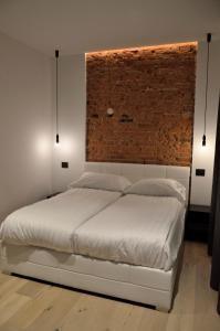 a bedroom with a white bed with a brick wall at Junior Suite agli Archetti in Torri del Benaco