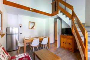 a kitchen and dining room with a wooden table and a staircase at Résidence Odalys Le Hameau du Mottaret in Méribel