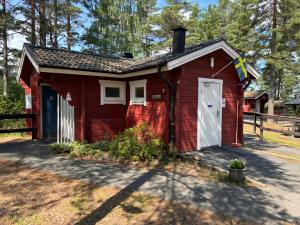 a red shed with a white door and a fence at Hyltena Stugby in Jönköping