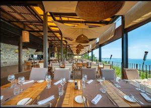 a dining room with tables and chairs and the ocean at Kaliakria Pearl Resort in Topola