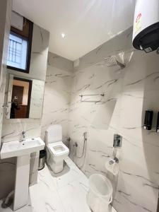 a white bathroom with a toilet and a sink at RS Galaxy Near AIMS Rishikesh in Rishīkesh