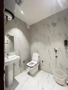 a white bathroom with a toilet and a sink at RS Galaxy Near AIMS Rishikesh in Rishīkesh +4 photos