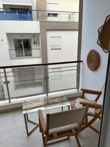 a balcony with a glass table and chairs and a building at Zaineb in Hammamet Sud +3 photos