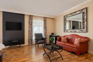 a living room with a red couch and a mirror at Protea Hotel by Marriott Kimberley in Kimberley