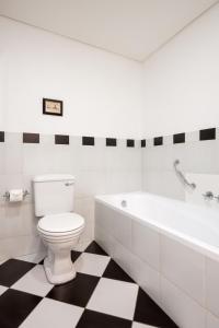 a white bathroom with a toilet and a bath tub at Protea Hotel by Marriott Kimberley in Kimberley +84 photos